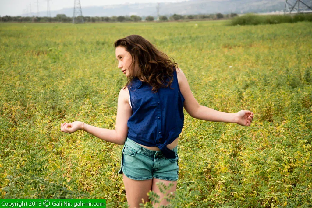 Girl in a blue shirt dancing in a green field